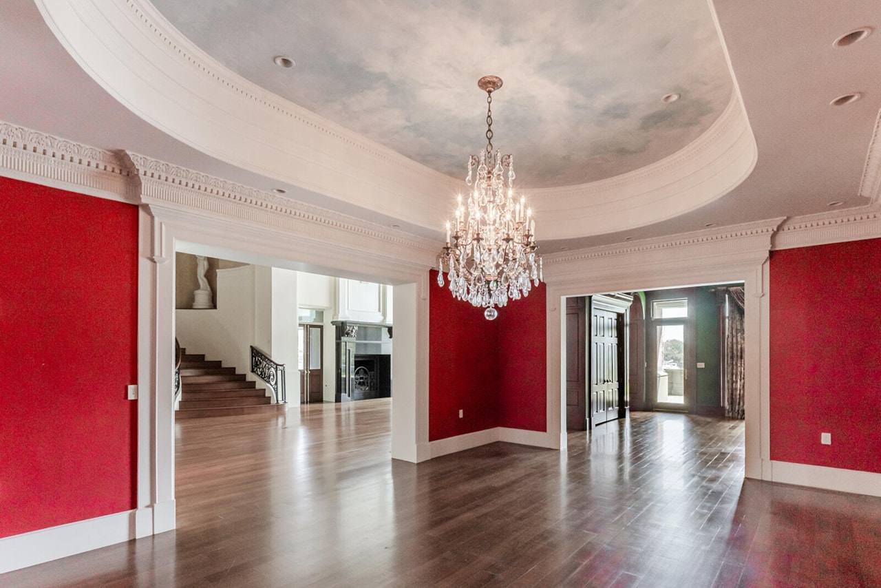 A formal sitting room with crimson silk-finished walls, a domed cloud-painted ceiling and a crystal chandelier